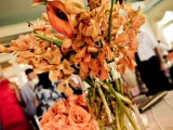 a colorful floral centerpiece of bright fall blooms and candles around is a nice idea for a colorful fall wedding