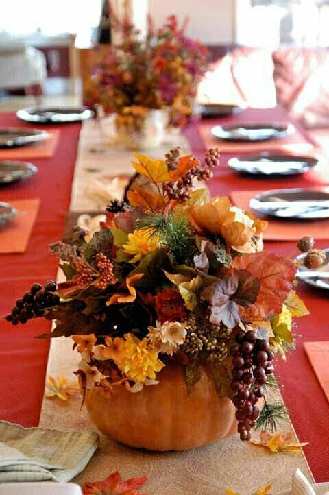 a pumpkin with bright blooms, dried foliage, berries and fruit is a nice fall wedding centerpiece idea