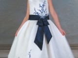 a white sleeveless A-line flower girl dress with navy floral patterns and a navy sash and a bow is very bold