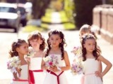 white A-line maxi dresses with berry-hued sashes, pastel bouquets for a whole group of flower girls