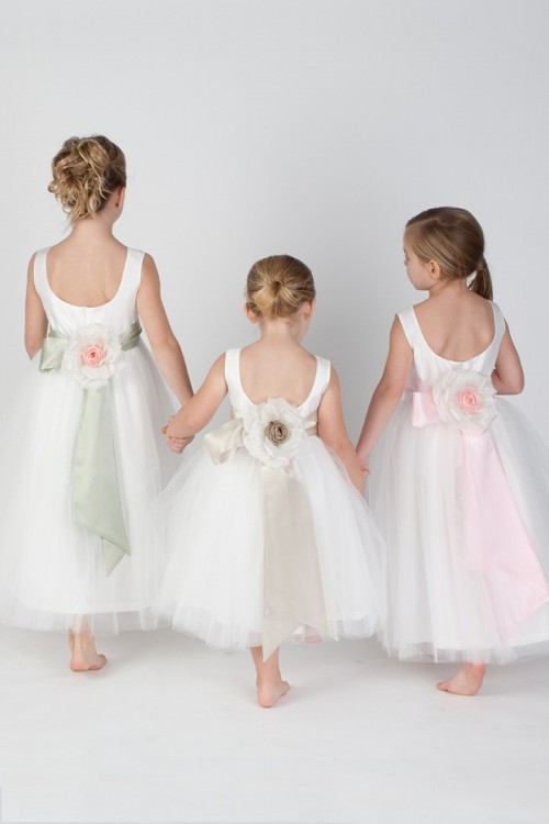 white and blush sleeveless flower girl dresses with cutout backs, flowers and ribbons on the backs for a refined look