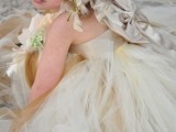 a tan flower girl dress with a tulle skirt, a shiny silky bodice and a fabric bow and fabric blooms as a headpiece