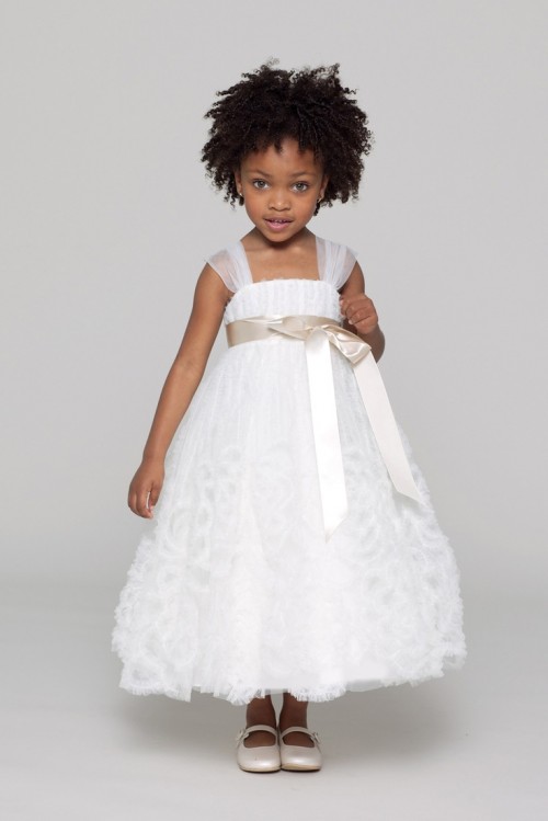a white A-line flower girl dress with sheer cap sleeves, a sash and a floral skirt is a bold and cool solution
