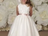a white A-line midi flower girl dress with a floral bodice and a pleated skirt, a blush sash and a large floral headpiece