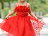 a red polka dot flower girl dress with a ruffle bodice and a layered skirt, spaghetti straps for a bold touch of color