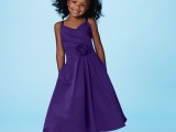 a purple A-line midi dress with a pleated skirt, a layered bodice and a fabric flower for a bold touch