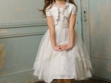 a white midi flower girl dress with lace appliques, a small ruffled bolero for a classic and chic look