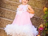 a pink a-line flower girl dress with white feather detailing plus a pink feather headpiece is a bright look for a glam wedding