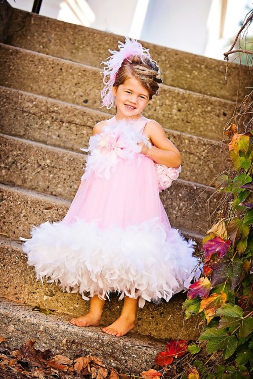 a pink a-line flower girl dress with white feather detailing plus a pink feather headpiece is a bright look for a glam wedding