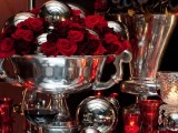 a bold Halloween wedding centerpiece of shiny bowls and vases, burgundy and red roses and black call lilies is very sophisticated