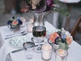 a bold and moody Halloween wedding centerpiece of a metal jug, purple blooms, branches and dried touches is a statement idea