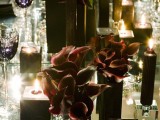 a moody Halloween wedding centerpiece of black vases with deep purple callas and black sculptural candles is amazing