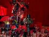 a dramatic Halloween wedding centerpiece in black and red, with branches, red blooms and black candles plus floral arrangements