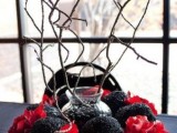 a dramatic Halloween wedding centerpiece of black glitter skulls, red flowers and branches going up is a very cool and bold idea