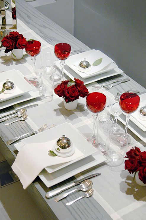 a stylish Valentine's Day wedding table in white, with metallic touches, red glasses and a red rose arrangement is very elegant and very chic