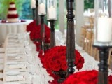 a stylish vintage Valentine’s Day wedding table in neutrals, with dark wooden candleholders and white candles, red roses and silver is amazing