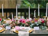 a chic and elegant Valentine’s Day wedding table with a lush greenery, hot pink and white blooms, candles in brass candleholders, gold chargers and cutlery and printed plates