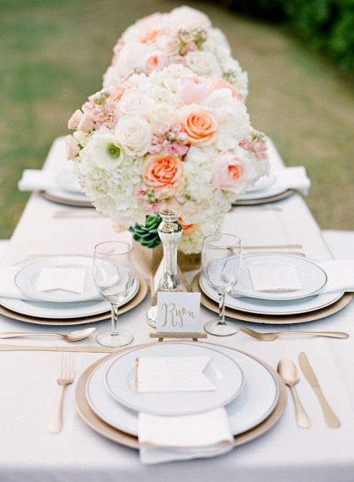 an elegant Valentine's Day wedding tablescape with chic white linens, blush blooms, peachy touches and gold rimmer plates and chargers
