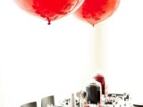 a black, white and red Valentine’s Day wedding tablescape with black and white porcelain, a red runner and red balloons, striped and red napkins
