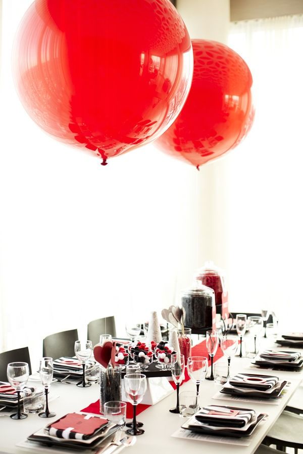 A black, white and red Valentine's Day wedding tablescape with black and white porcelain, a red runner and red balloons, striped and red napkins