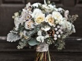 a frozen winter wedding bouquet with white blooms, pale greenery, evergreens and berries
