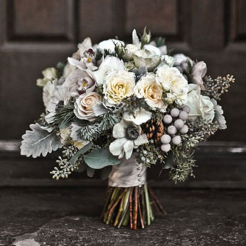 a frozen winter wedding bouquet with white blooms, pale greenery, evergreens and berries