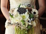 a white and green winter wedding bouquet with berries, lotus seeds and cascading elements plus feathers