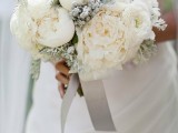 a frozen-looking winter wedding bouquet with white blooms and pale greenery plus silver ribbons