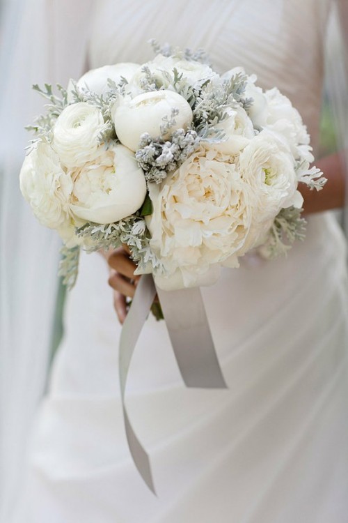 a frozen-looking winter wedding bouquet with white blooms and pale greenery plus silver ribbons