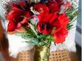 a bold red and greenery wedding bouquet with a gold wrap is amazing for a holiday wedding
