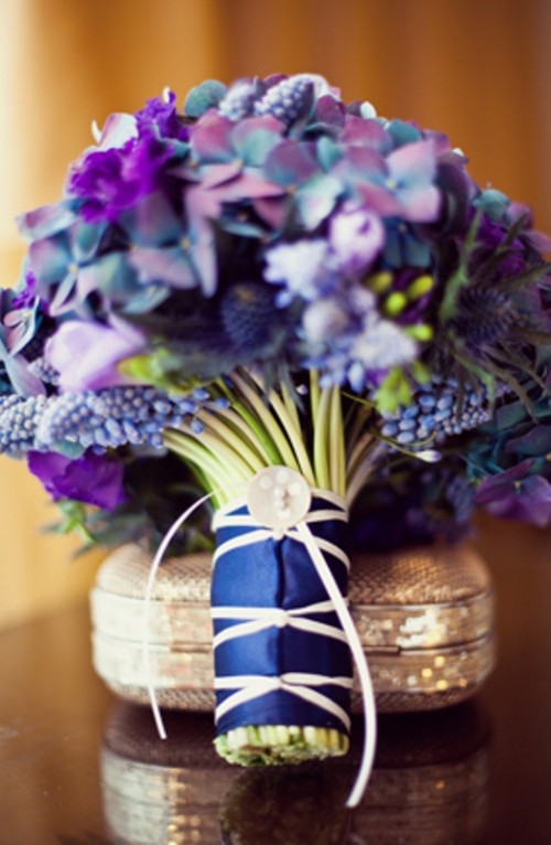 a bold purple and blue wedding bouquet with a navy wrap and a large button for your 'something blue' at the wedding