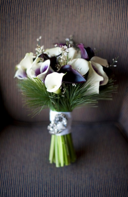 an elegant winter wedding bouquet with white and deep purple blooms plus greenery