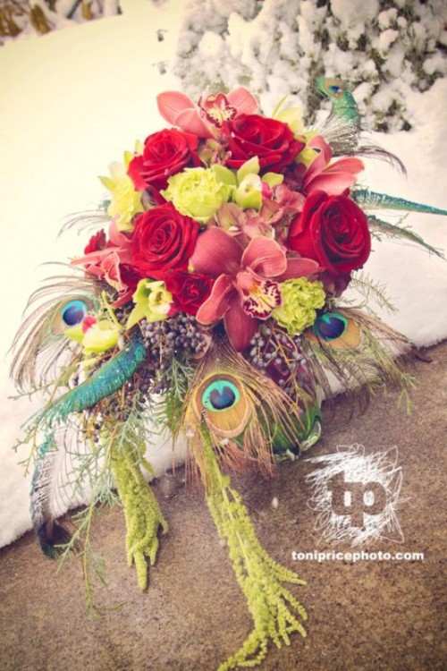 a bright and colorful winter wedding bouquet with red, yellow and green blooms plus peacock feathers for a bold touch