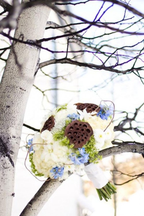 a winter wedding bouquet of blue and white blooms, with lotus seeds plus green hydrangeas and white ribbons
