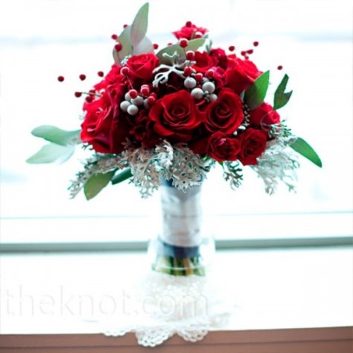 a red winter wedding bouquet with pale greenery, foliage and berries plus a white wrap for a contrast