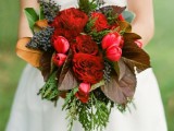 a bold red winter wedding bouquet with berries, evergreens and dark foliage for a colorful touch