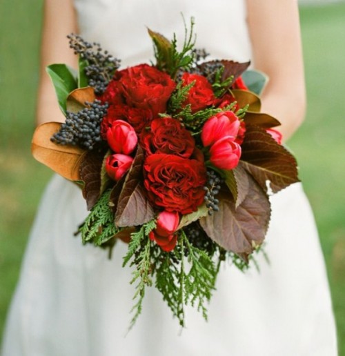 a bold red winter wedding bouquet with berries, evergreens and dark foliage for a colorful touch