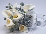 a pale winter wedding bouquet with white callas, silver pinecones, blooms and berries
