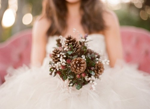 a winter wedding bouquet with pinecones, greenery and white berries for a cute winter look