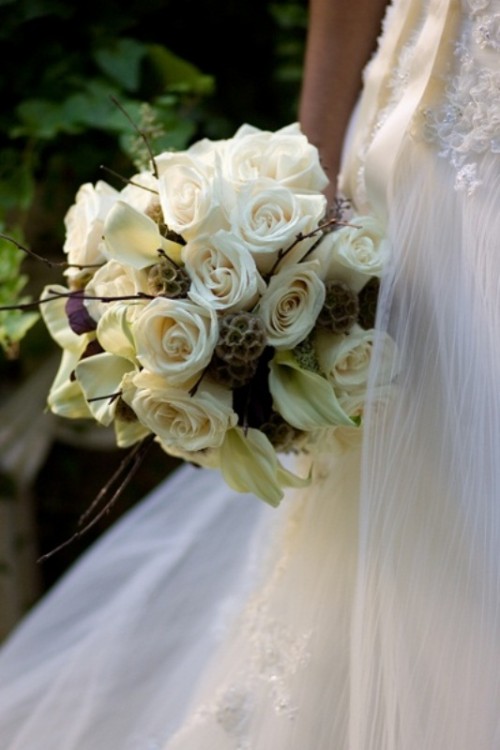 a white winter wedding bouquet with white roses and callas, twigs is a cool idea with a rustic feel