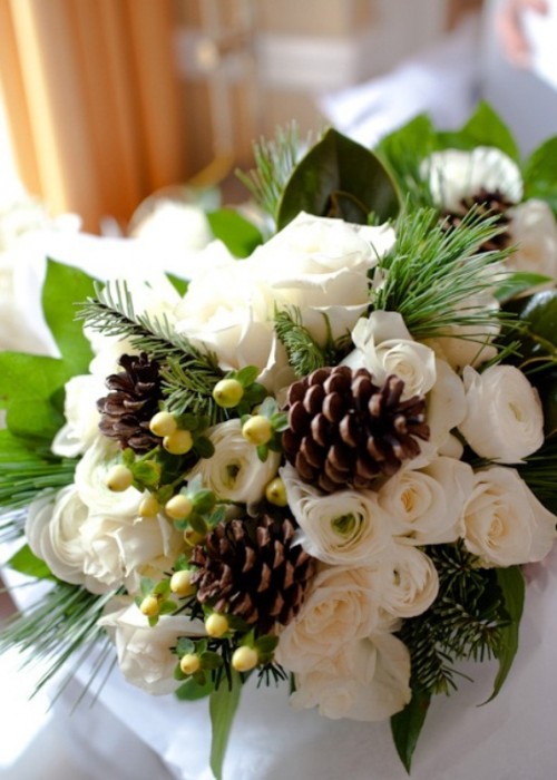 a rustic winter wedding bouquet with white blooms, greenery, berries and pinecones