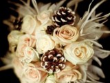 a textural winter wedding bouquet with white and blush blooms, pinecones plus feathers