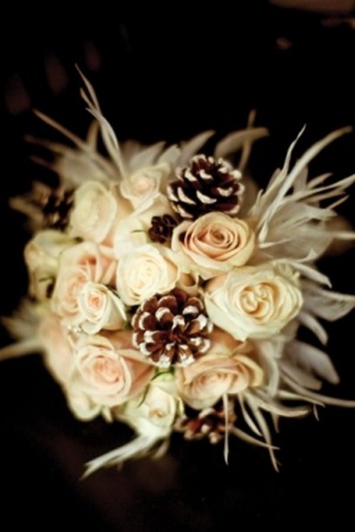 a textural winter wedding bouquet with white and blush blooms, pinecones plus feathers