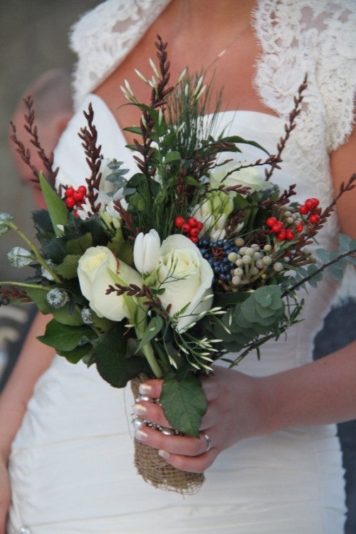a textural winter wedding bouquet with white blooms, red and blue berries, foliage and much texture