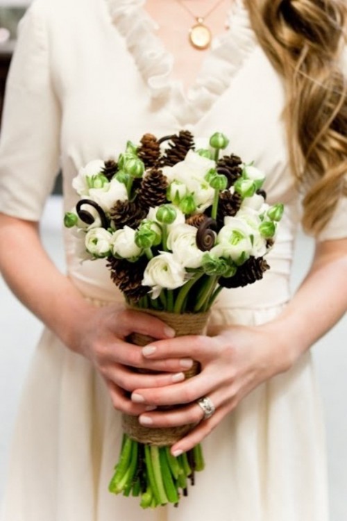 a winter wedding bouquet of white and green blooms, lotus and pinecones for a rustic touch