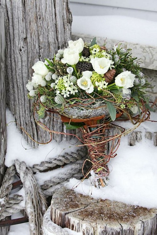 a beautiful winter wedding bouquet of greenery, white blooms, berries and lotus seeds in a vine wrap for a rustic touch