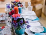 a super bright boho tablescape in turquoise and red, with candles, blooms, bright textiles