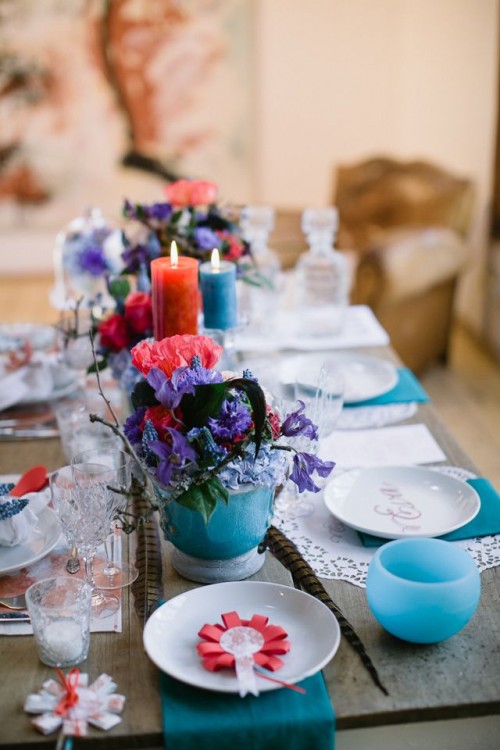 a super bright boho tablescape in turquoise and red, with candles, blooms, bright textiles