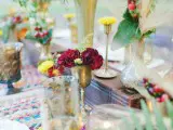 a bright boho tablescape with colorful placemats, colored glasses and super bright florals and herbs