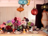 a colorful tablescape with bright lamps hanging down, colorful florals, fruits and colored glasses